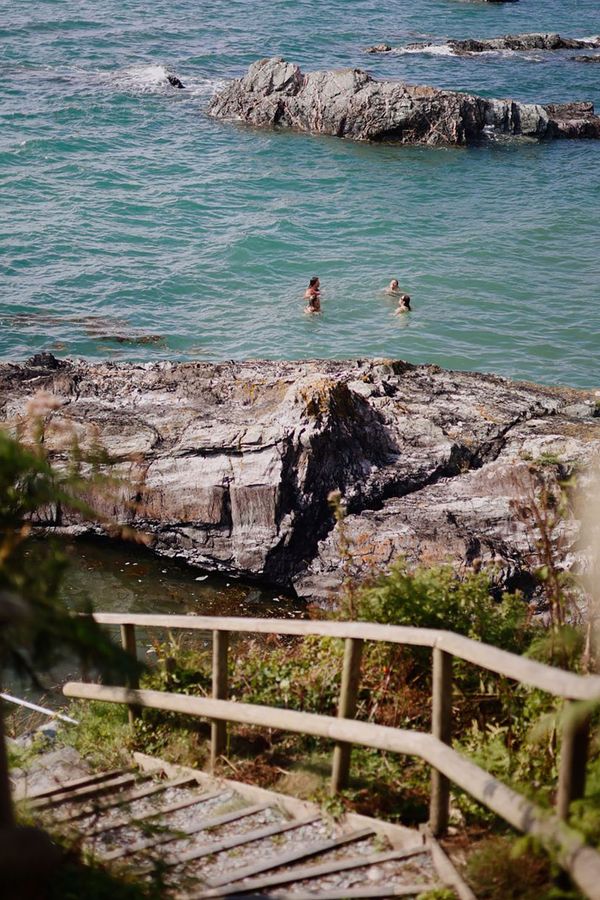 View of people swimming from the steps leading to private beach at Polhawn Fort