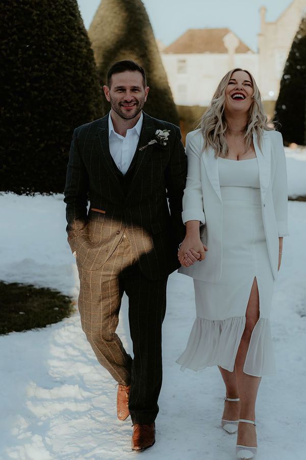 A couple holding hands in the snow for winter wedding