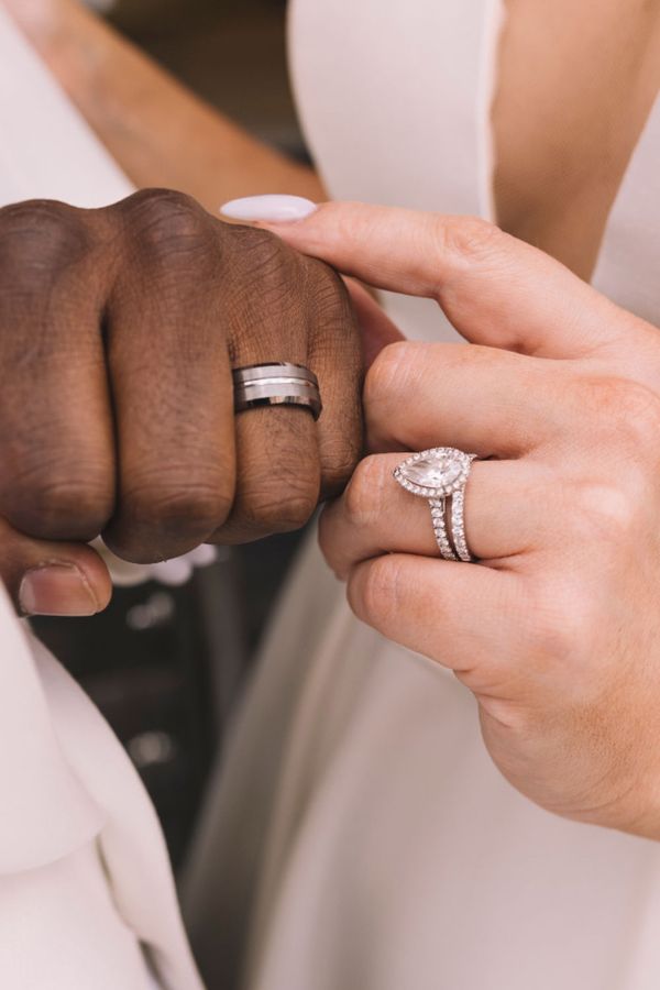 Bride and groom wearing diamond engagement ring and wedding bands
