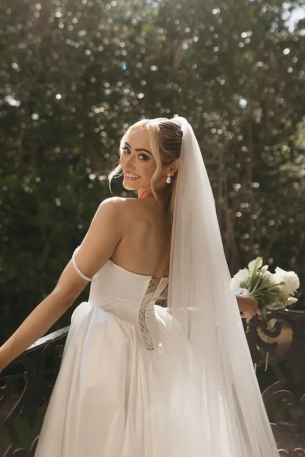 Bride in princess wedding dress with veil and white flower bouquet