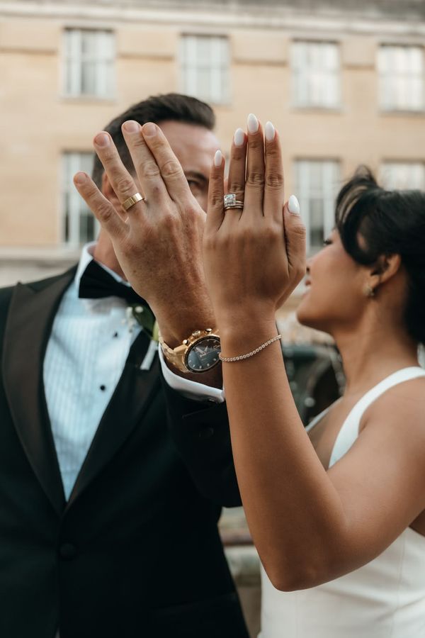 Bride and groom put their left hand up to the camera to show off their new wedding rings and alternative engagement ring