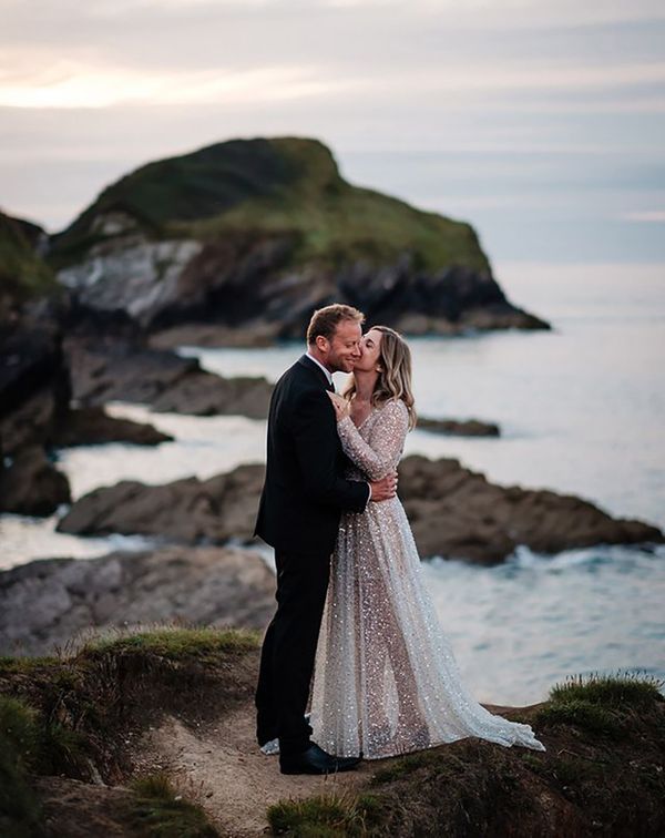 bride wearing a sparkly bespoke wedding dress by the sea on wedding day with groom