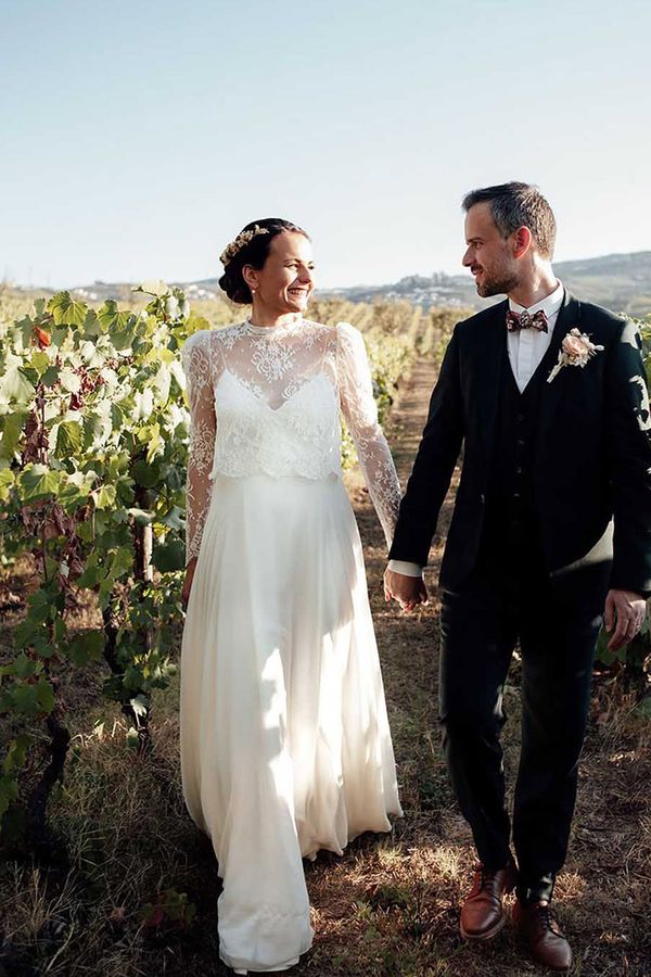 couple holding hands while walking through grapevine rows during their destination wedding at portugal vineyard venue