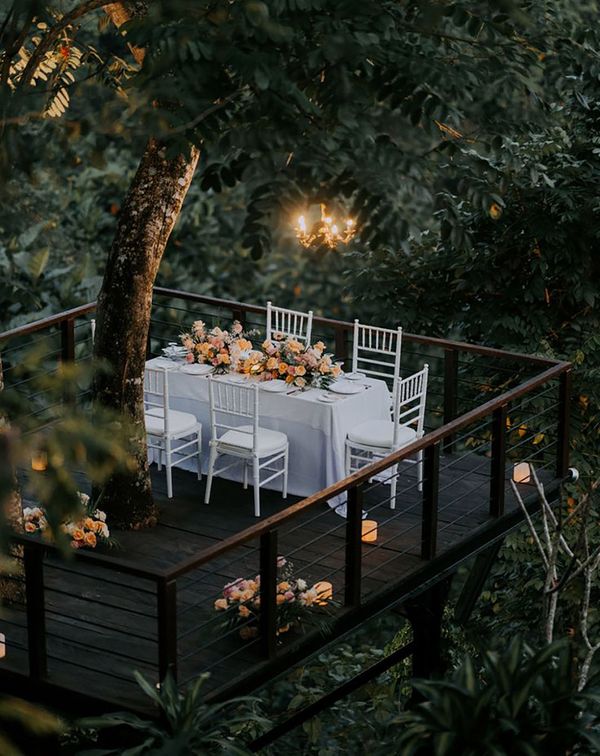 White wedding tablescape and decorations with colourful yellow flowers and pillar candles high in the jungle in Bali