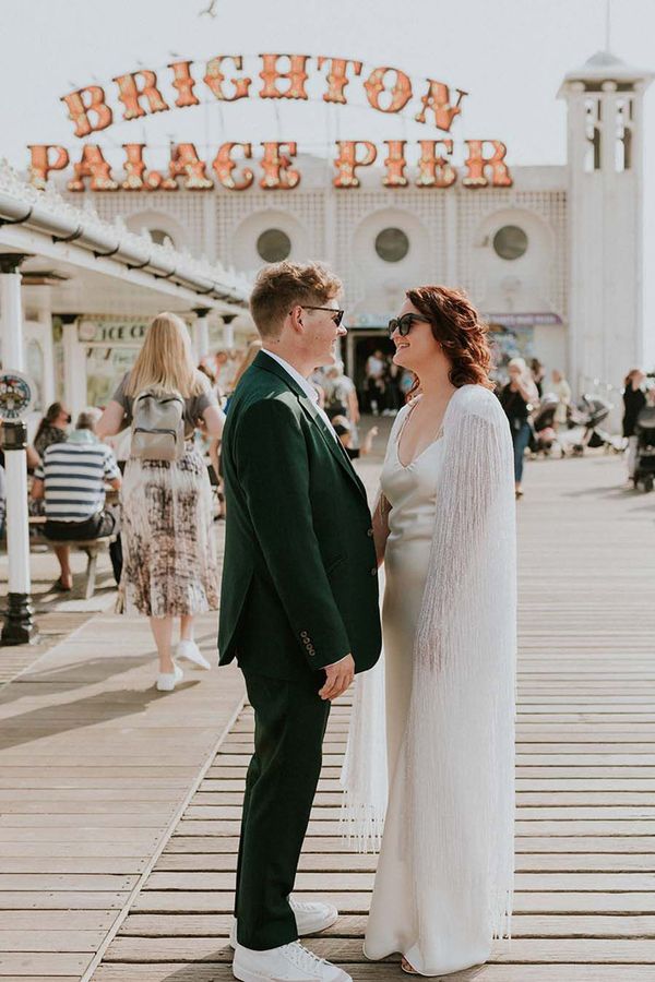 Couple getting married in Brighton with the iconic pier sign behind them