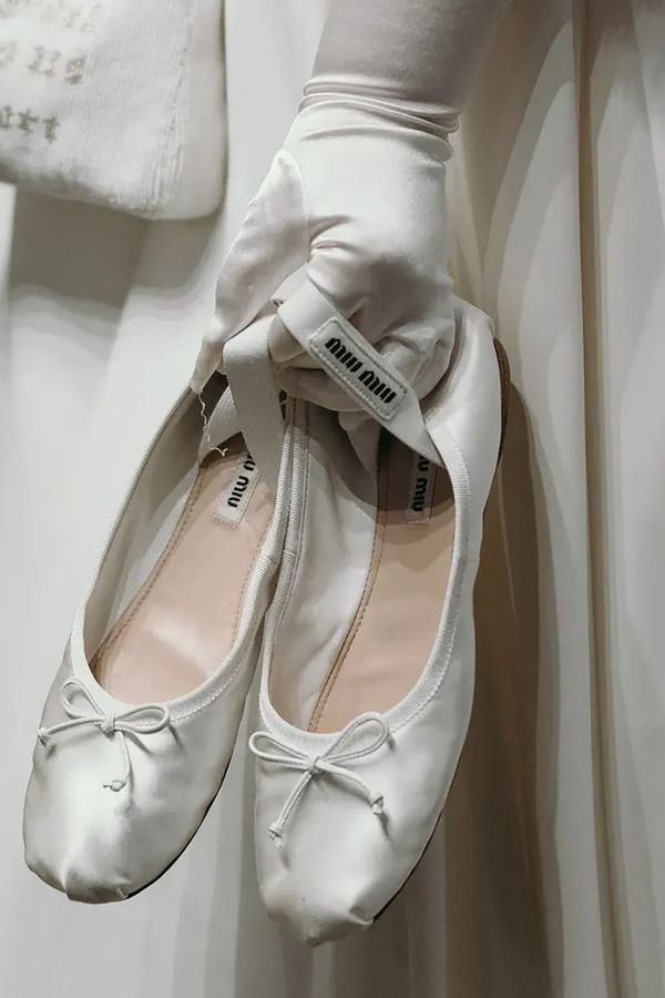 Bride holding white ballet flat pumps from Miu Miu