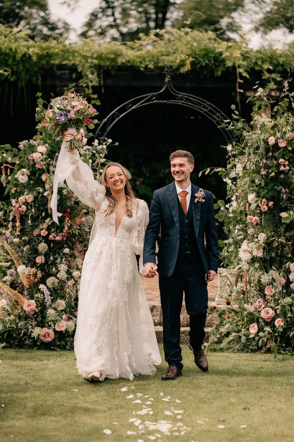 Beautiful garden inspired wedding arch filled with seasonal flowers - Image by Emilie May Photography