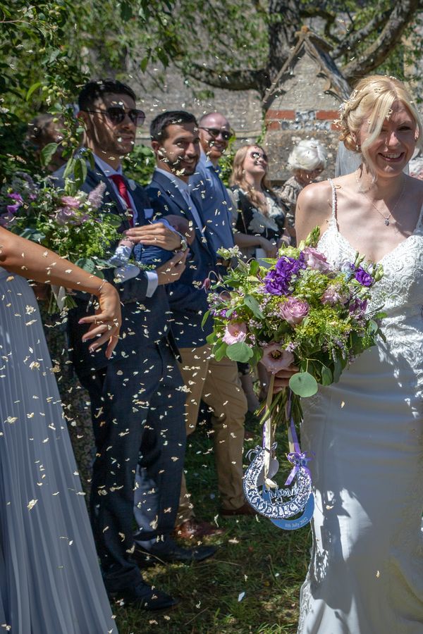Alex & Nicola emerge from the church in a shower of confetti, hand in hand & beaming with pure joy. Nicola's stunning bouquet of purple lisianthus, blush roses & lush greenery perfectly complemented the warm summer sunshine as their guests cheered them on. 