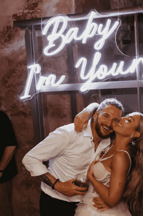 A gorgeous couple in front of their Neon Daddy LED Neon Sign