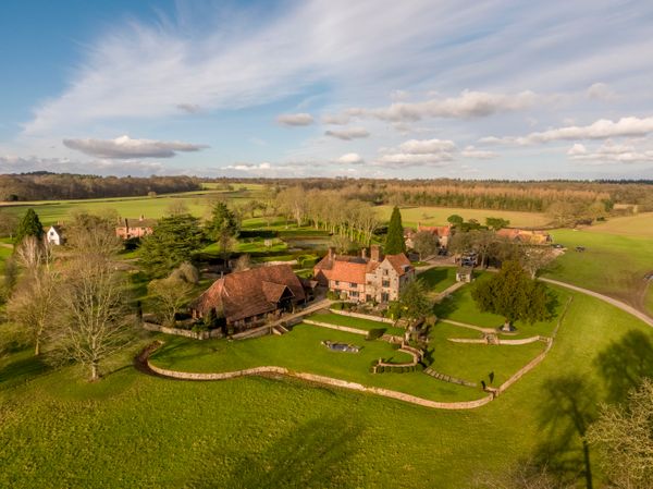 A stunning aerial view of Burrow Farm Estate, showcasing the beautifully restored main house and barn nestled within rolling countryside, surrounded by manicured gardens, woodland and expansive open fields in the heart of the Chiltern Hills. Image credit: Burrow Farm Estate