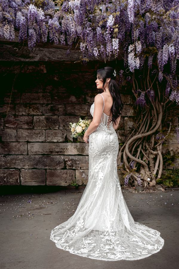 Bride portrait beneath wisteria captured during a relaxed Manchester wedding celebration by By Elle.