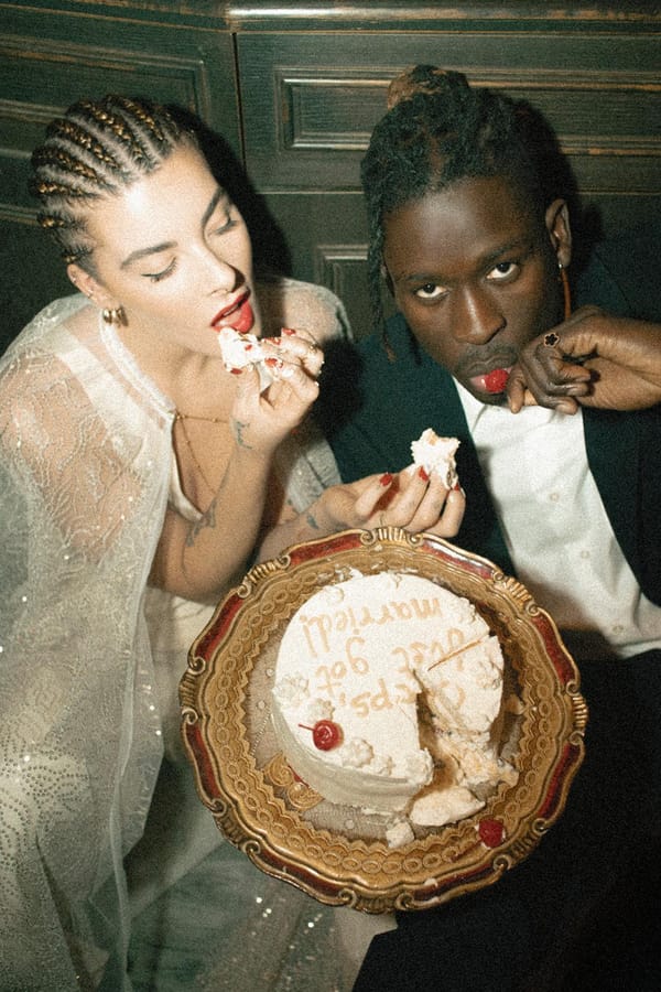 Wedding cake, fingers first. A couple diving into cake on a vintage gold platter, with red lipstick, lace and a playful disregard for etiquette. Your Love, Your Rules. Photography by Alice Santella.