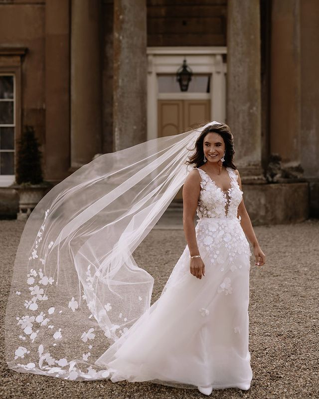 Bride in Mira Zwillinger appliqué wedding dress with floral embroidered veil.