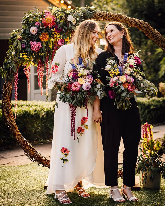 Two brides stand next to moongate decoration at seasonal at The Parlour wedding