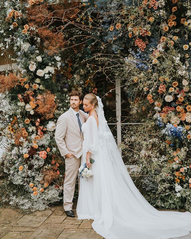 Bride and groom in front of large floral display at Sezincote House.