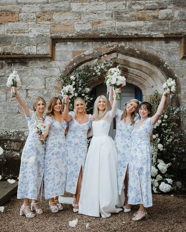 Bride with bridesmaids in blue patterned dresses at their wedding venue.