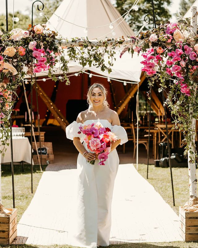 Tipi wedding with the bride in off the shoulder dress holding pink bouquet
