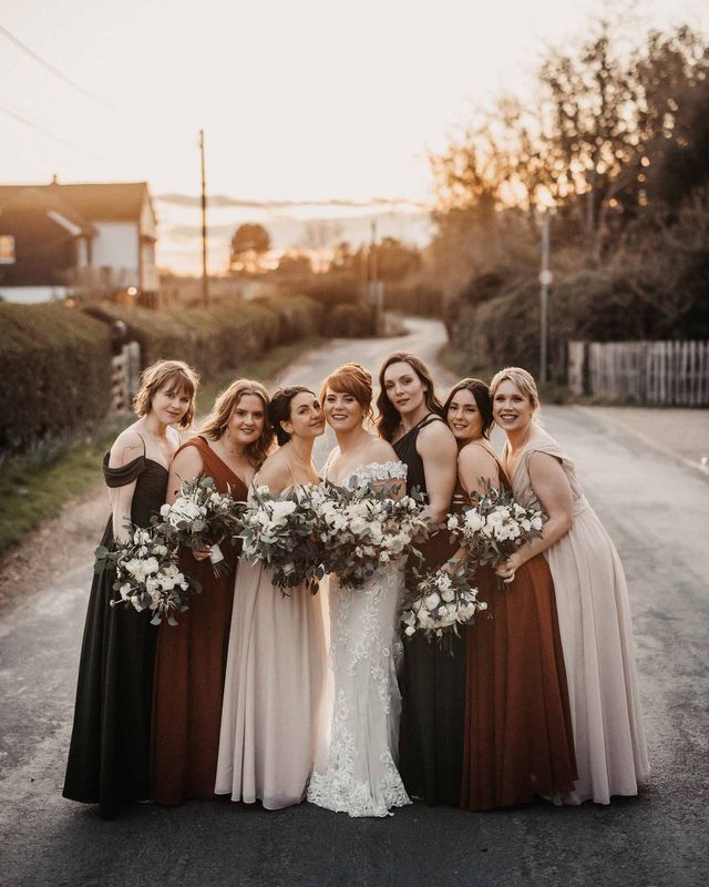 Bride in lace Maggie Sottero wedding dress with bridesmaids in earth toned dresses for wedding at Cooling Castle Barn.