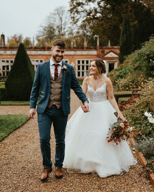 Bride in Blush by Hayley Paige holding autumnal wedding bouquet with groom in blue suit for Oxnead Hall wedding,