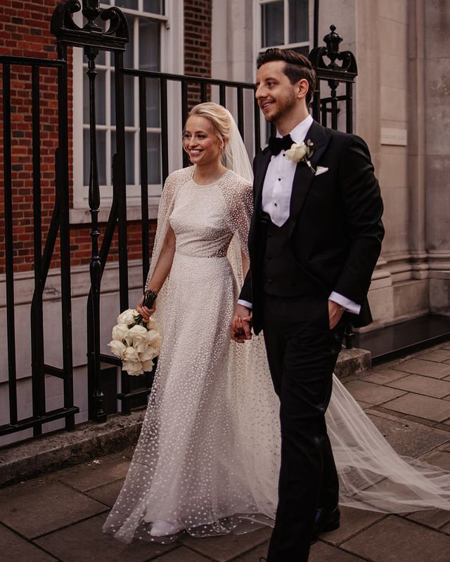 Bride in a shimmery Jesus Peiro wedding cape with groom in black tie.