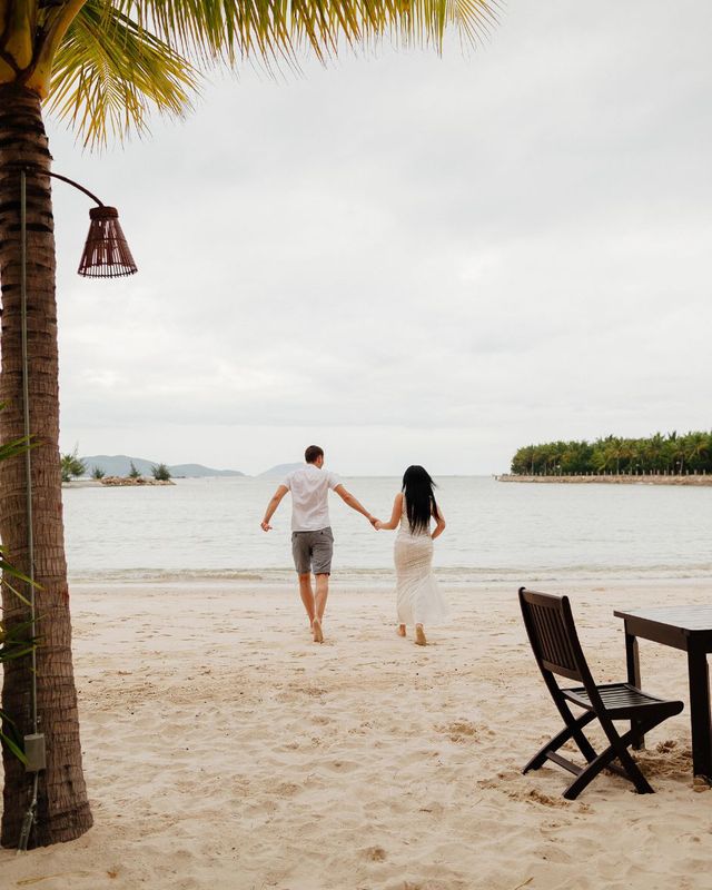 couple joyfully running along the beach towards the sea, celebrating their honeymoon