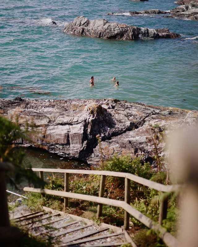View of people swimming from the steps leading to private beach at Polhawn Fort