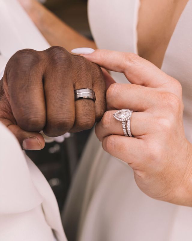 Bride and groom wearing diamond engagement ring and wedding bands