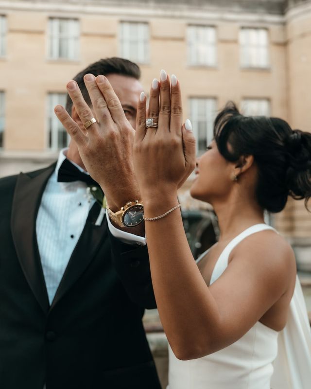 Bride and groom put their left hand up to the camera to show off their new wedding rings and alternative engagement ring