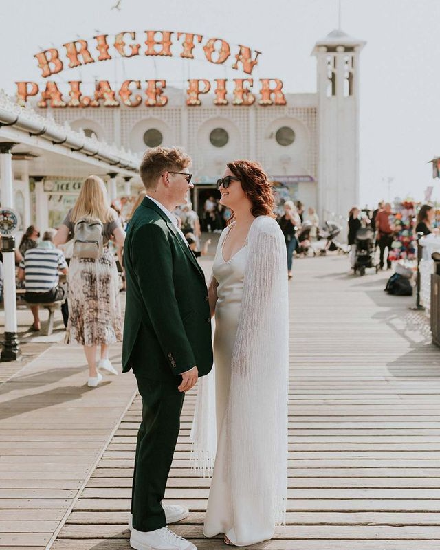 Couple getting married in Brighton with the iconic pier sign behind them