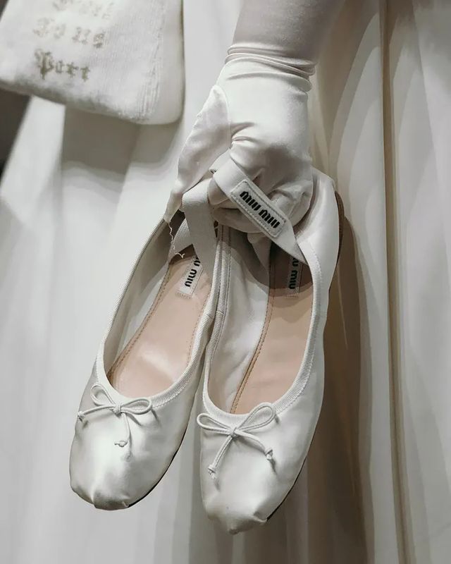 Bride holding white ballet flat pumps from Miu Miu