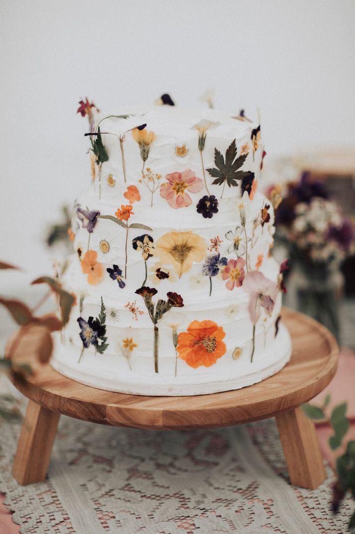 Flower pressed wedding cake on a wooden cake stand 