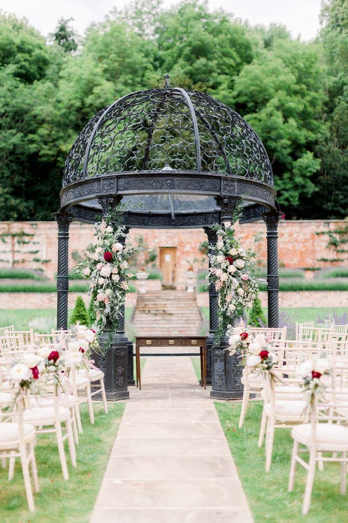 Outdoor alter at Garthmyl Hall with white chairs, a black gazebo and pink floral decorations