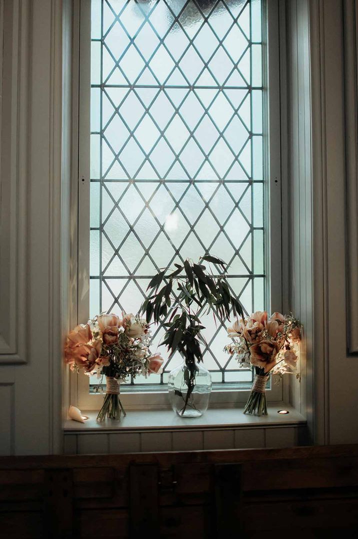 Wedding flower arrangements in glass jar vases on window ledge at The Dougarie Boathouse - wedding venues Scotland