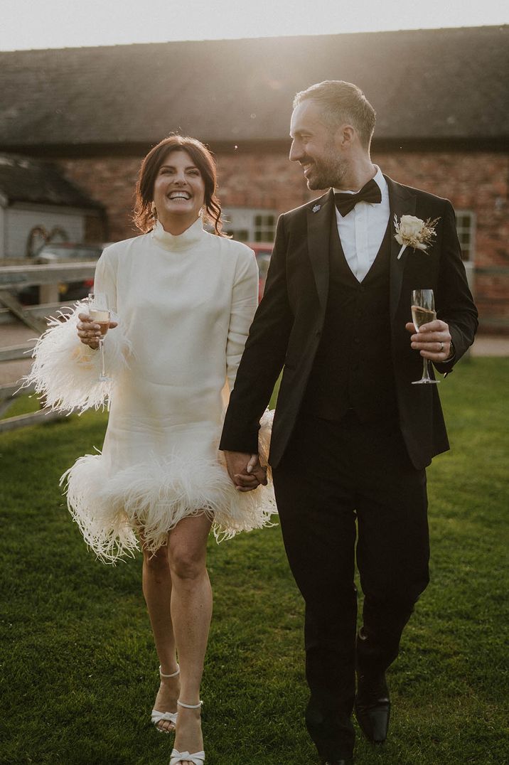 Winter wedding dress for bride with long sleeves and short skirt covered in white ostrich feather cuffs 