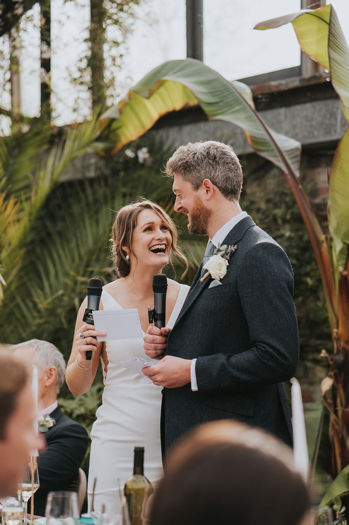 Bride and groom both holding microphones for their joint wedding speech at glasshouse wedding 