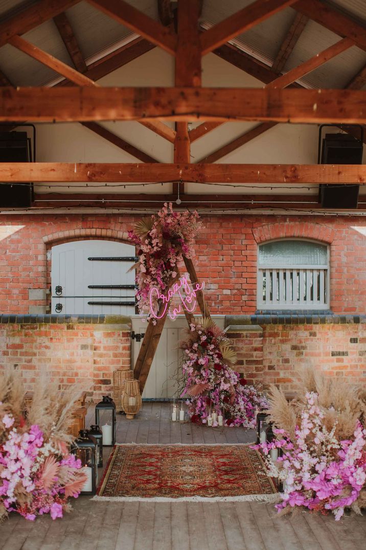 rustic barn wedding aisle decor with crazy in love neon sign, dried flowers and wooden benches