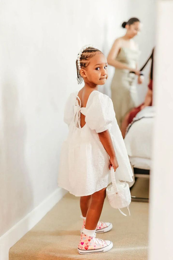 Young bridesmaid wearing white bridesmaid dress with bow detail and pearl headband