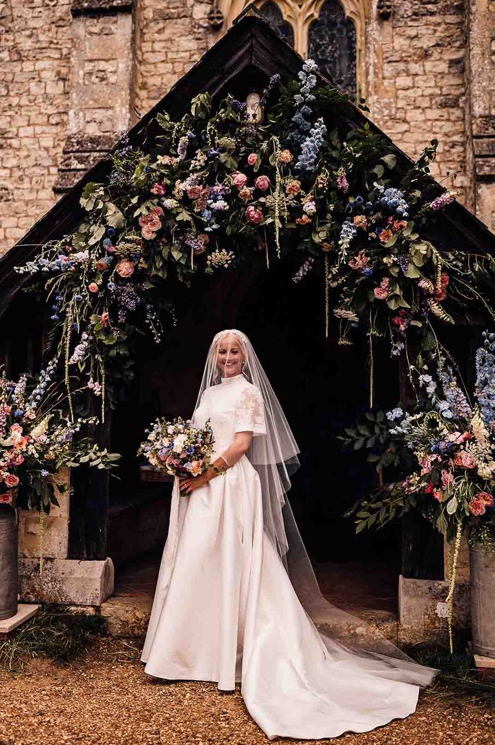 Bride in a delicate lace Jesus Peiro wedding dress with pink and blue wedding flowers