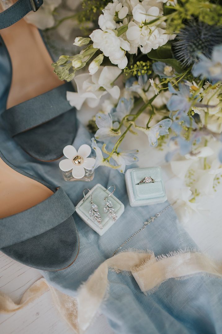 Blue wedding shoes with blue and white wedding flower bouquet with blue velvet jewellery box with diamond ring and earrings 