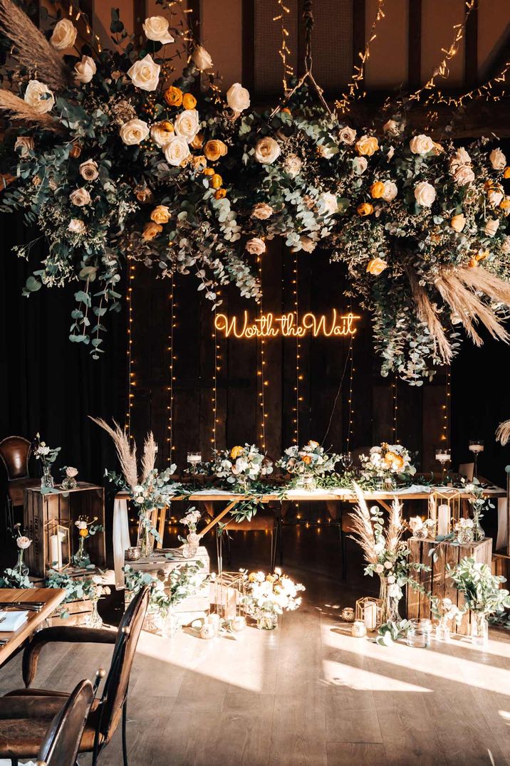 White, gold and yellow rose detail hanging florals above a neutral, warm wedding tablescape at Tythe Barn wedding venue