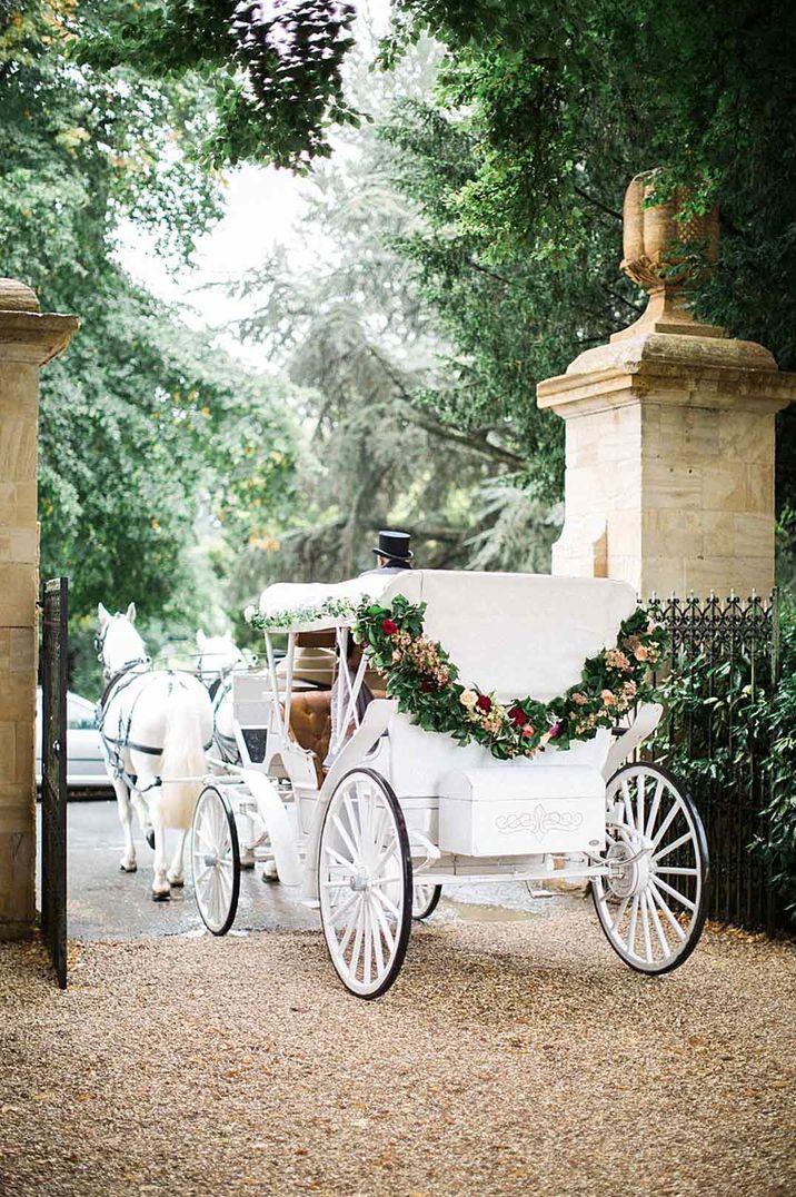 White wedding horse-drawn carriage with floral wreath decorations - transport section of wedding budget spreadsheet 