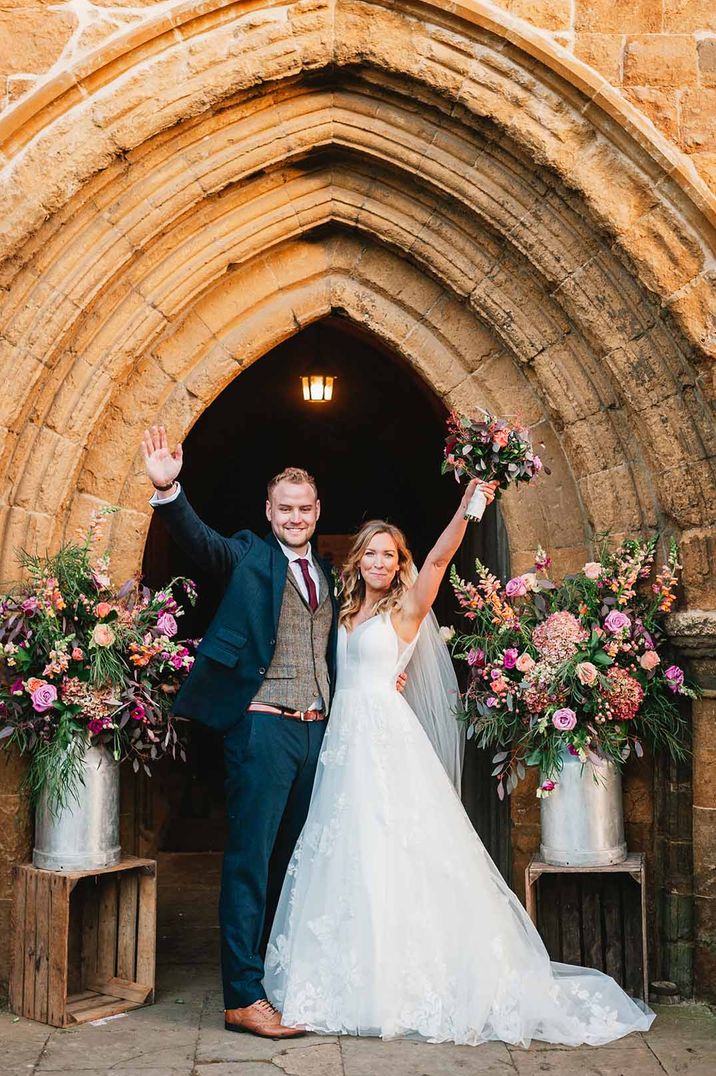 Bride in princess layered wedding dress and cathedral length with her groom in dark three piece suit