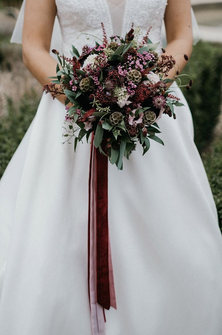 Pink, red, and green wedding bouquet with pink wax flower tied with velvet red ribbon 