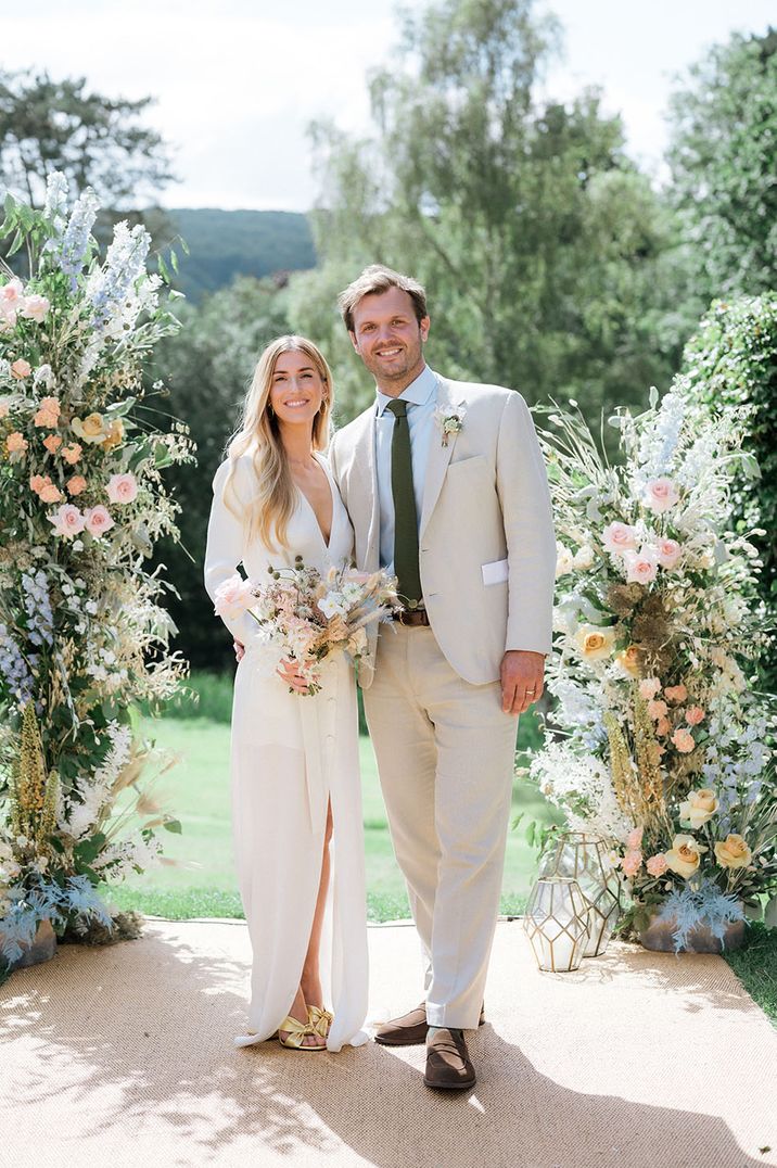 Bride and groom at outdoor wedding with colourful pastel wedding flower columns