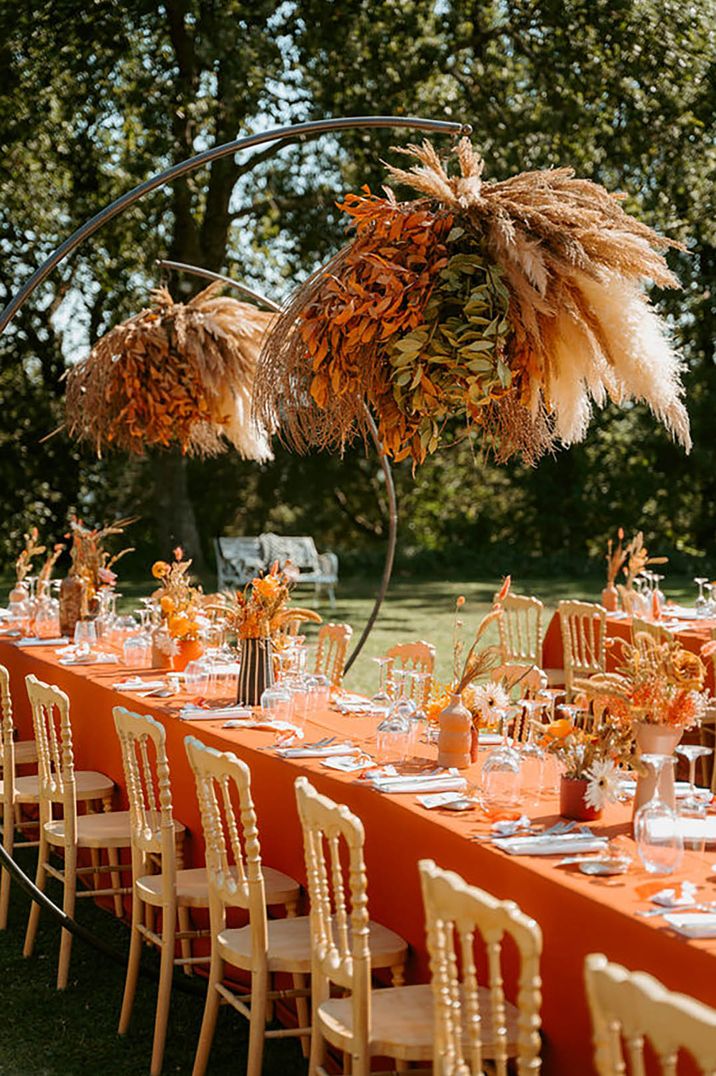 Orange-themed table decor with dramatic overhanging flowers by Federica Mazzieri Photography