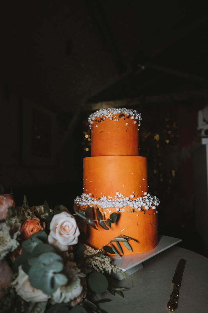 Three tier bright orange wedding cake with pearls 