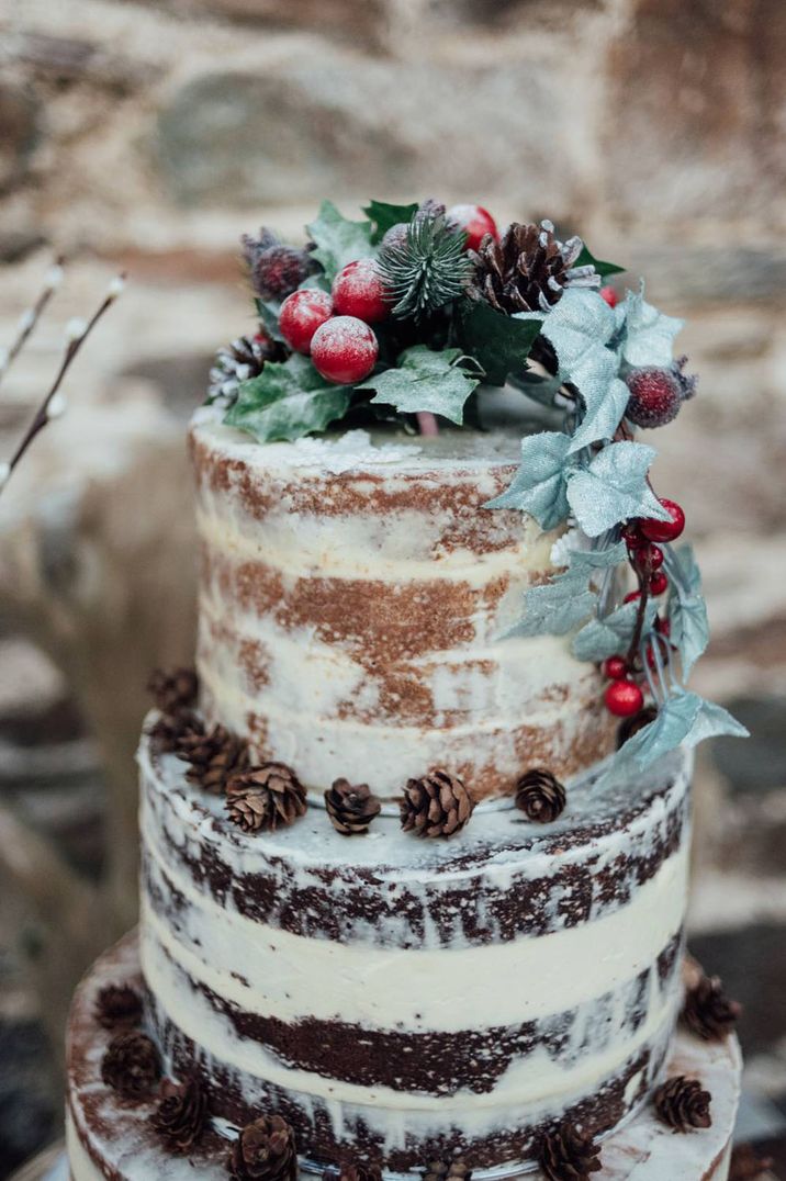 Winter wedding cake with winter berries and pinecones on semi naked iced wedding cake 