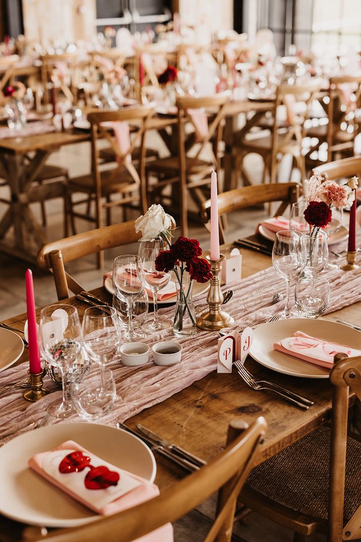 Light and bright pink candles with red candles in gold candle holders with white rose flowers in bud vases with red carnations 