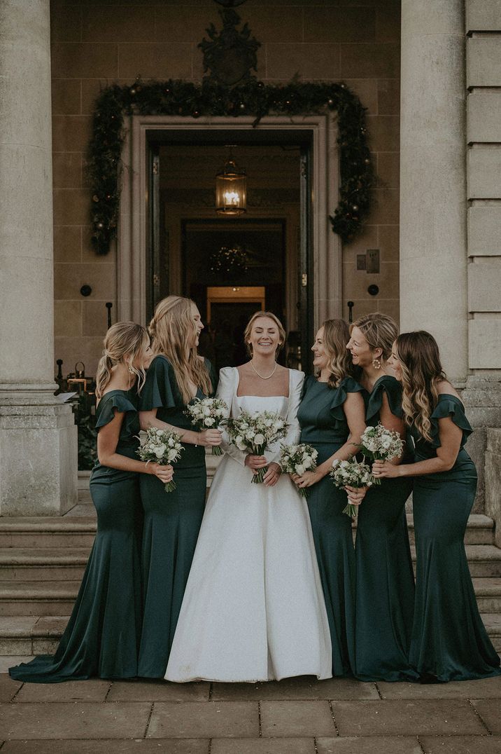 Bride in long sleeve white wedding dress and long green bridesmaid dresses