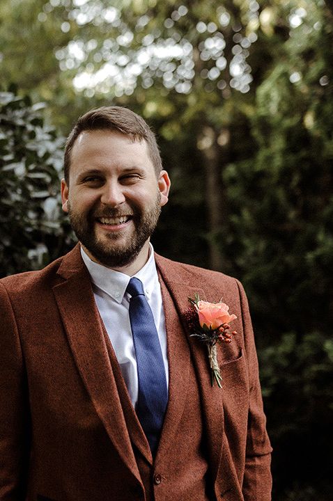 Groom in burnt orange textured suit and boutonnière 